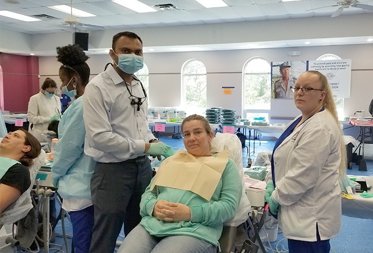 Dental patient with dentist and team member at community event