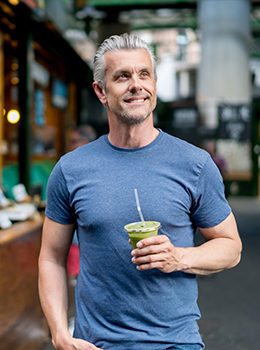 Older man with dental implants holding drink