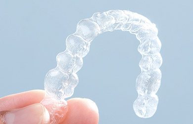 Hand holding an Invisalign tray